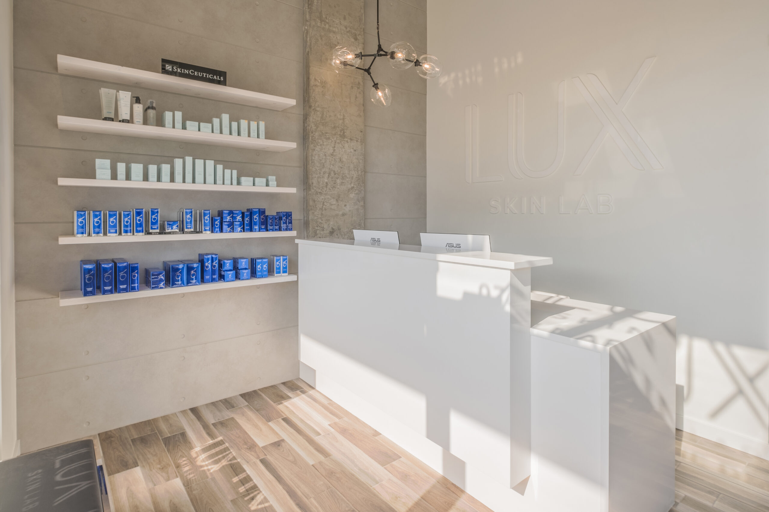 Interior of the LUX Skin Lab clinic featuring a white desk and a wall shelf filled with products.